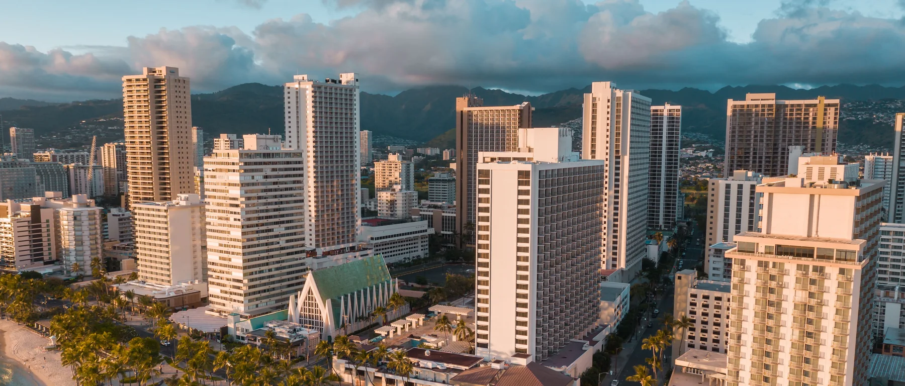 Vista aérea de los hoteles frente a la playa de Waikiki y la avenida Kalākaua junto a la arena al atardecer